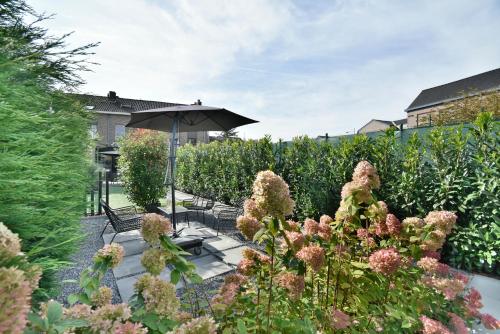 um pátio com bancos e um guarda-sol num jardim em Stylish Home near Maastricht Alicias house em Lanaken