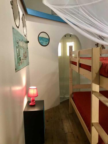 a bedroom with a bunk bed and a table with a lamp at KANOUAN in Deshaies