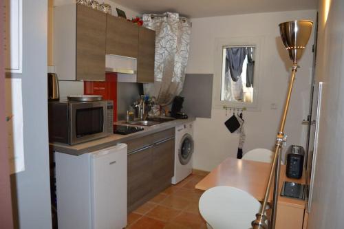 une petite cuisine avec un évier et un micro-ondes dans l'établissement Studio plage, parking gratuit et terrasse privée., à Saint-Mandrier-sur-Mer