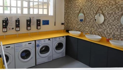 a laundry room with three washing machines and two sinks at ALBERGUE de Caldas de Reis URRACA in Caldas de Reis