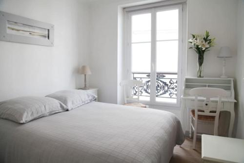 une chambre blanche avec un lit et une fenêtre dans l'établissement The Charming Ramey, à Paris