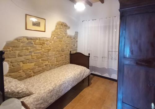 a bedroom with a bed and a stone wall at B&B CorteBonomini entire home in Sasso