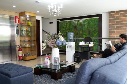 a man sitting in a living room reading a book at Hotel Portón Sabaneta in Sabaneta