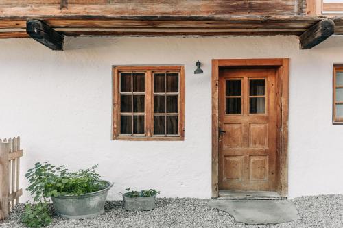a house with a wooden door and two potted plants at Bauernchalet elbacher gütel - Exklusives Ferienhaus am Starnberger See in Eurasburg