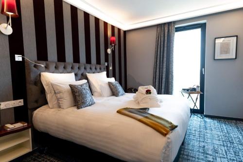 een hotelkamer met een groot bed met witte kussens bij Hôtel Dali Val d'Europe in Chanteloup-en-Brie