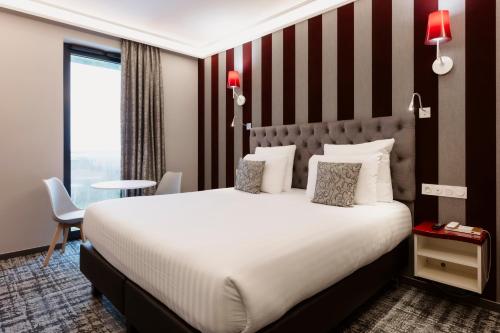 um quarto de hotel com uma cama grande e uma janela em Hôtel Dali Val d'Europe em Chanteloup En Brie