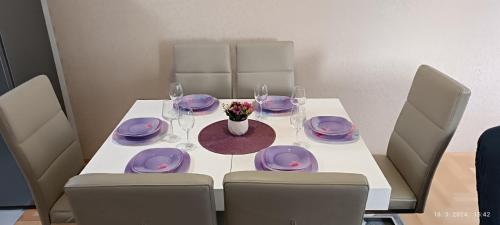 a table with purple plates and a vase of flowers on it at Apartman LARA in Pirot