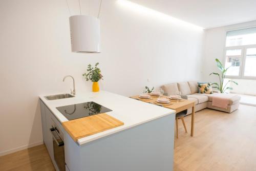 a white kitchen with a sink and a living room at Mareas de Carril a 50m de la playa in Vilagarcia de Arousa