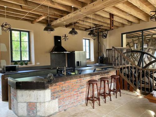 une cuisine avec un comptoir en briques et quelques tabourets dans l'établissement Authentique moulin à eau du ⅫⅠe siècle, à La Vernelle