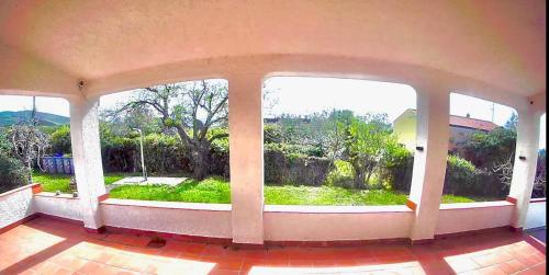 an empty room with a view of a garden through windows at Sardinia SeaBreeze Villa IUN R2178 in Castelsardo
