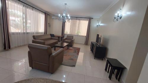 a living room with a couch and a tv and chairs at Cozy 3BR w/pool & gym in Dar es Salaam