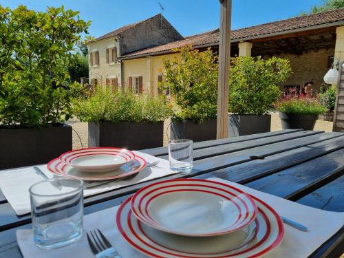 a wooden table with red and white plates on it at Gites de Cognac in Bréville