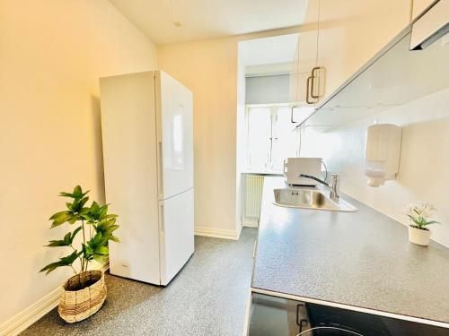 a kitchen with a white refrigerator and a sink at aday - Villa Firenze - 2 Bedrooms Bright Apartment in Aalborg