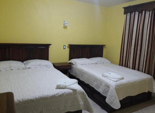 two beds in a hotel room with white sheets at Hotel curvita in San Cristóbal