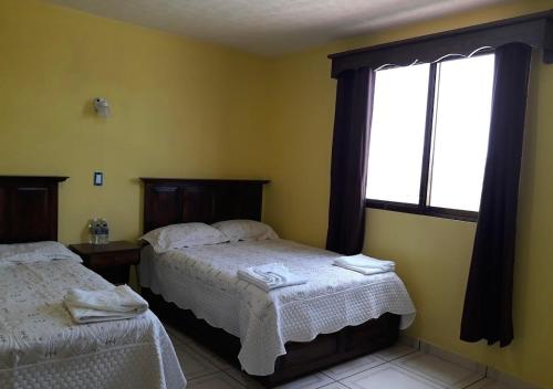a bedroom with two beds and a window at Hotel curvita in San Cristóbal