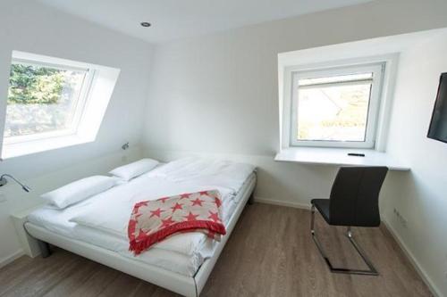 een slaapkamer met een bed, een bureau en 2 ramen bij Strandkoje-Landhaus-Tadsen in Westerland