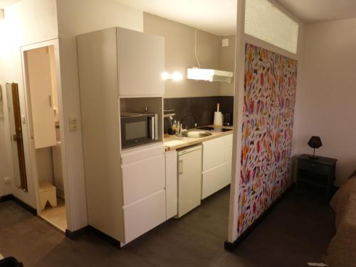 une petite cuisine avec des armoires blanches et un micro-ondes dans l'établissement Vert Marin, à Rochefort