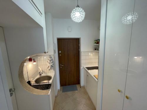 a bathroom with a sink and a mirror and a door at ComeWa Apartments in Warsaw