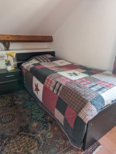 uma cama com uma colcha num quarto em Chambre dans une maison pendant les Jeux Olympiques em Rambouillet