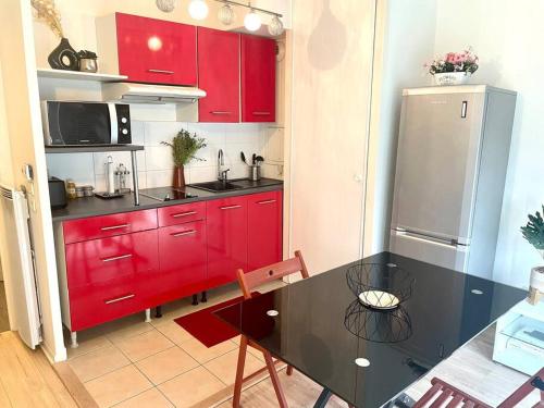 une cuisine avec des placards rouges et une table noire dans l'établissement Cosy Studio proche de Paris idéal pour les JO, à Argenteuil