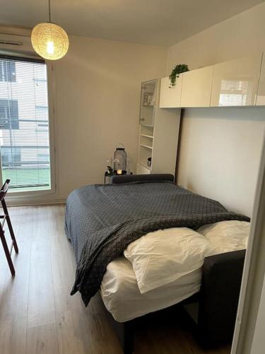une chambre avec un lit dans une pièce avec une fenêtre dans l'établissement Cosy Studio proche de Paris idéal pour les JO, à Argenteuil