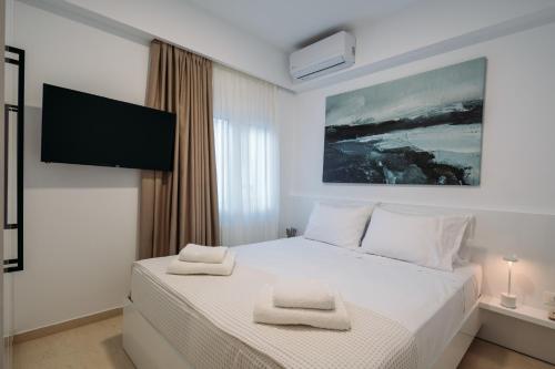a bedroom with a white bed with a flat screen tv at ELiXiR 2 Luxury apartments in Agios Nikolaos
