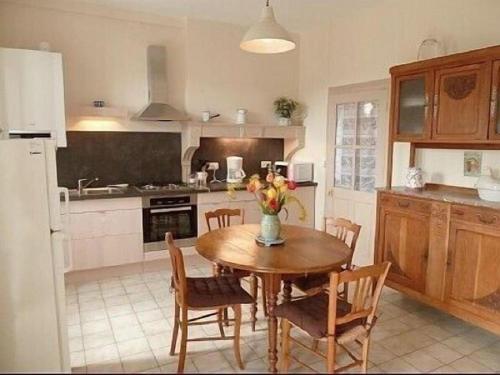 una cocina con una mesa de madera con sillas y un jarrón de flores en GITE DU VIGNERON en Chassey-Le-Camp