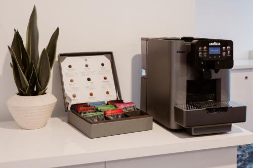 a coffee maker sitting next to a gift box next to a plant at Hotel Dali Val d'Europe, Tapestry Collection by Hilton in Chanteloup-en-Brie