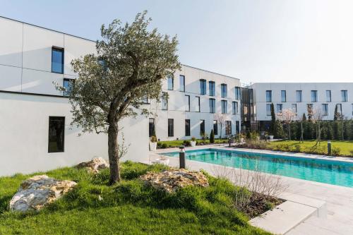 um edifício de apartamentos com uma piscina e uma árvore em Hôtel Dali Val d'Europe em Chanteloup En Brie