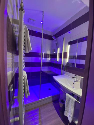 a purple bathroom with a sink and a shower at The Originals City - Hôtel Saint-Martial, Limoges Centre in Limoges