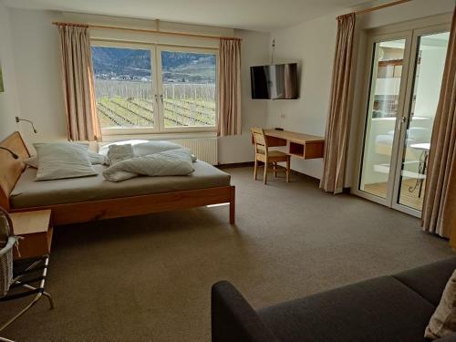 a bedroom with a bed and a desk and a window at Haus im Erlengrund in Coldrano