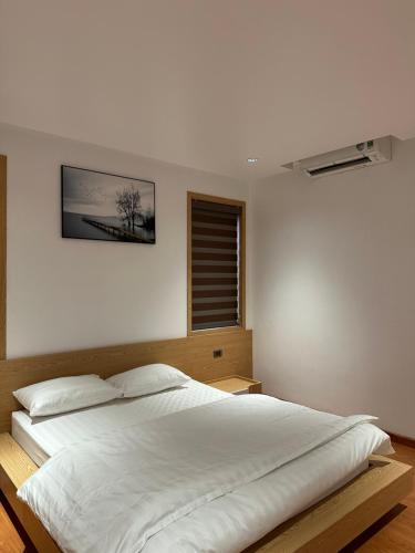 ein großes weißes Bett in einem Schlafzimmer mit Fenster in der Unterkunft La foret Vân Hoà villa 2 in Hanoi