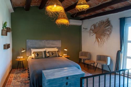 a bedroom with a bed and two chairs and two lights at Cal Mestre Casa Rural in Avinyonet