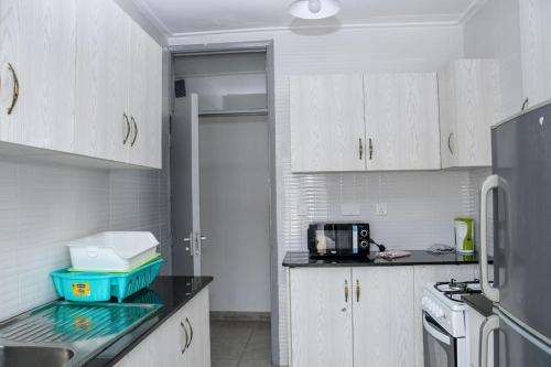 a kitchen with white cabinets and a black counter top at Familia@HeArt in Kakamega