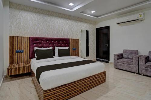 a bedroom with a large bed and a chair at OYO 82334 Hotel Keshri Inn in Prayagraj