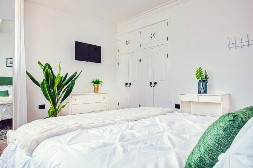 a white bedroom with a bed and a tv at Casa Palma 2 in La Paz