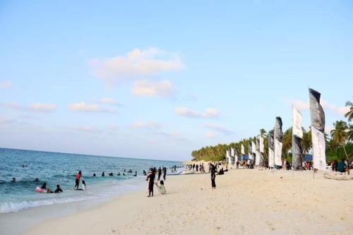 un gruppo di persone su una spiaggia con l'oceano di Secret Escape a Fuvahmulah