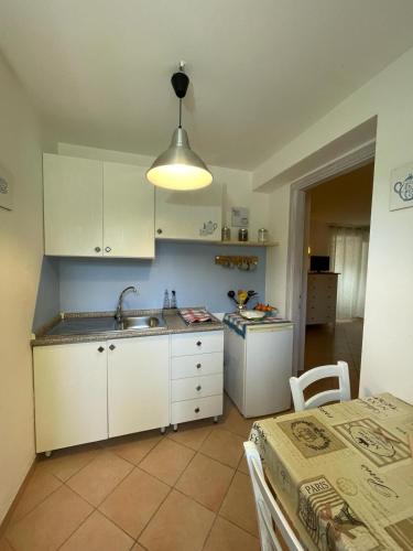 a kitchen with white cabinets and a sink and a table at Le Palme Holidays in Palmadula