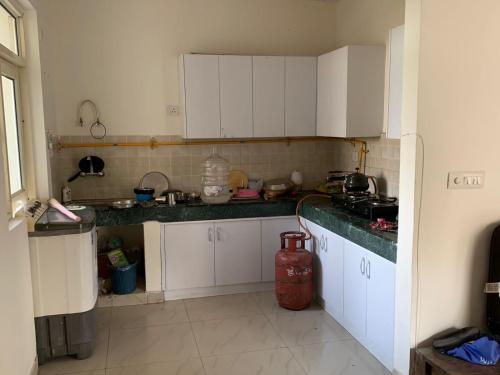 a kitchen with white cabinets and green counter tops at 2BHKapartment-Calm and natural in Faridabad