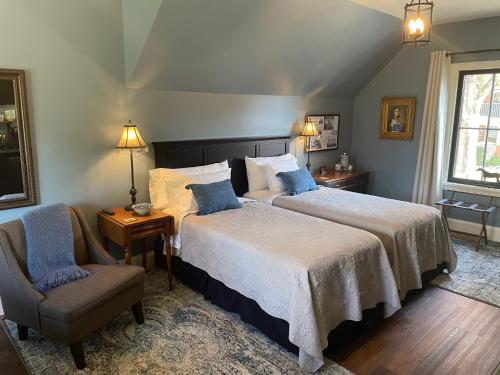 a bedroom with two beds and a chair at Stone's Throw Stratford in Stratford
