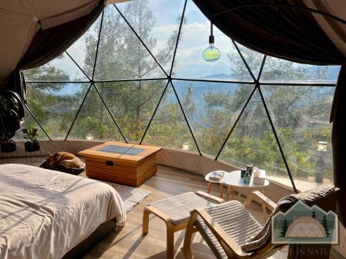 a bedroom with a bed and chairs in front of a large window at Dome in Nature in Larnaka