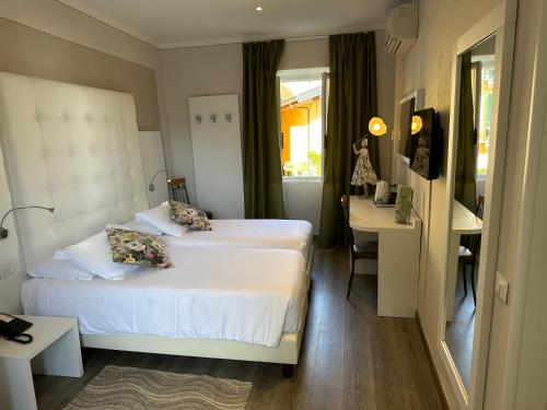 a hotel room with two beds and a desk at Albergo Pesce D'oro in Verbania