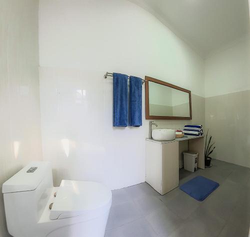 a white bathroom with a sink and a mirror at Hide Inn Blue in Nilandhoo