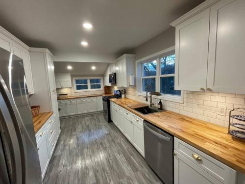 a large kitchen with white cabinets and wooden floors at Hilltop Haven w/Creek&Waterfall Dntwn McCaysville in McCaysville
