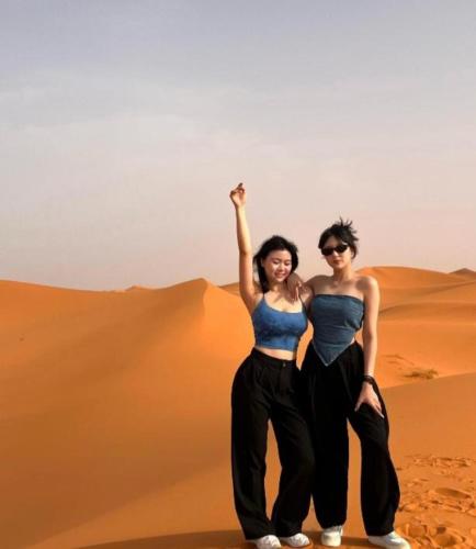 two women standing in the sand in the desert at Merzouga Luxurious Camp in Merzouga