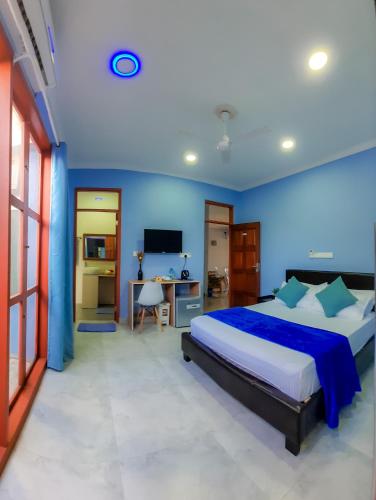 a bedroom with a large bed with blue walls at Hide Inn Blue in Nilandhoo