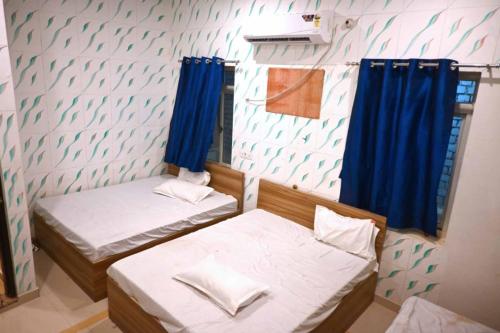 two beds in a room with blue curtains at Hotel Bhagwaan Das In Varanasi in Varanasi
