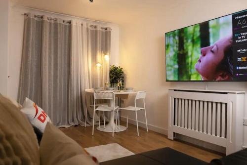 a living room with a table and a large flat screen tv at No 15 Modern Comfort in a Prime Southampton Location - Free Parking in Southampton