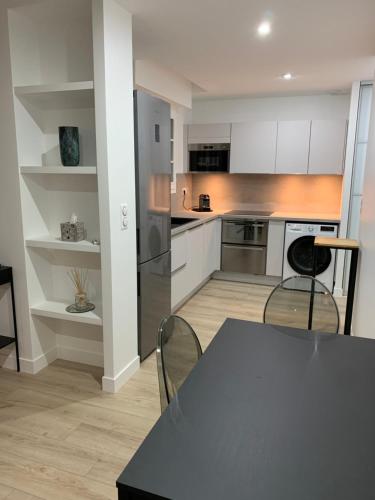 une cuisine avec des armoires blanches et une table et des chaises dans l'établissement Location Studio meublé Sceaux (proche Lakanal), à Sceaux