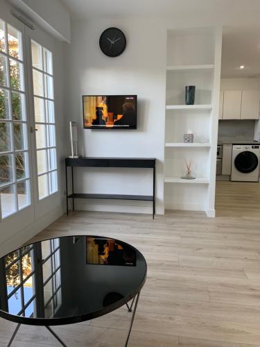 - un salon avec une table en verre et une télévision murale dans l'établissement Location Studio meublé Sceaux (proche Lakanal), à Sceaux